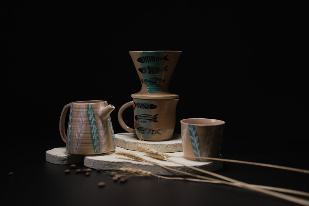 Set of ceramic coffee brewing equipment with decorative elements on a dark background